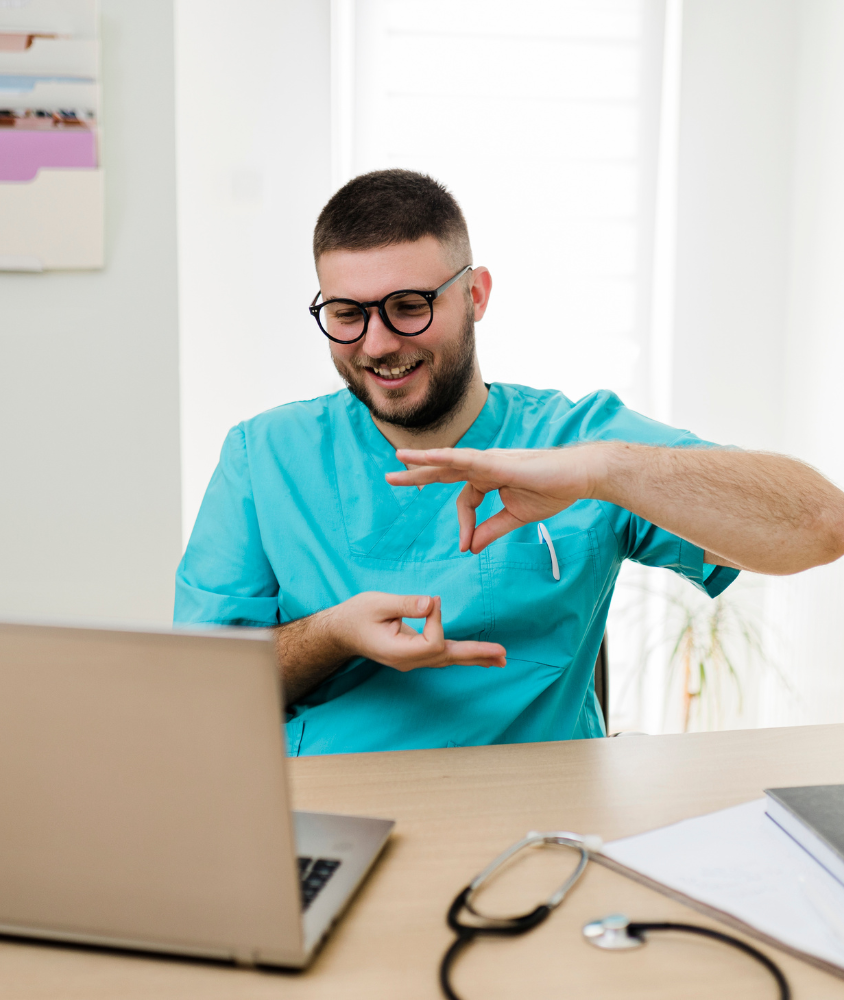 Inicio Profesional de la salud hablando en lengua de señas frente a un computador en una videollamada